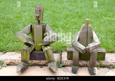 Holzfiguren sitzen in der Nähe von Wiese im Garten Stockfoto