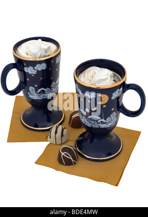 Zwei Kaffee-Dessert-Getränke sind garniert mit Schlagsahne und serviert mit Pralinen. Stockfoto