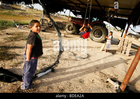 Kinder spielen auf einer improvisierten Schaukel in die unbekannte Beduinen Dorf von Al Araqeeb in der Wüste Negev, Israel Stockfoto