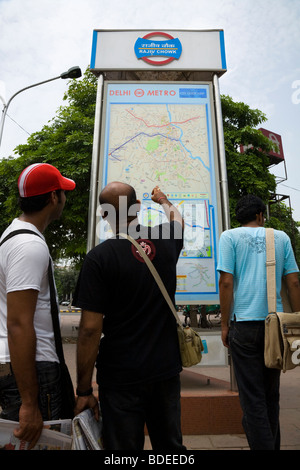 Indische Männer betrachten eine Informationen Anfahrtsplan von der Delhi Metro-System auf dem Display außerhalb Rajiv Chowk Station. Delhi, Indien. Stockfoto