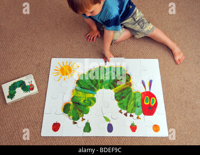 Kind schließt ein Puzzle von The Very Hungry Caterpillar Stockfoto