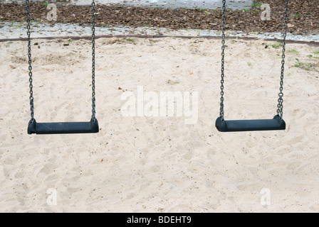 Zwei Kinderschaukeln auf einem Spielplatz mit Sand Stockfoto