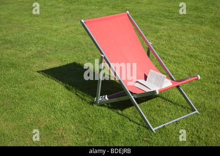 Taschenbuch auf roten Liegestuhl zu öffnen Stockfoto