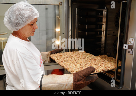 Frau aus einem Ofen in einer kommerziellen Bäckerei ein Tablett oder Cookies entfernen Stockfoto