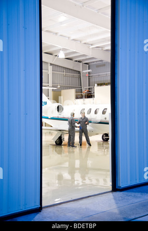 Zwei Flugzeugmechaniker mit Diskussion im Hangar neben Privat-jet Stockfoto