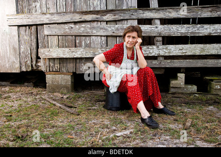 Senior Frau sitzt auf der Farm in der Nähe der Scheune sorgen Stockfoto