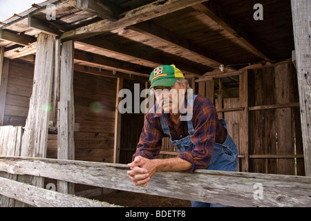 Portrait von senior Mann mit grünen Mütze stützte sich auf Holzzaun Stockfoto