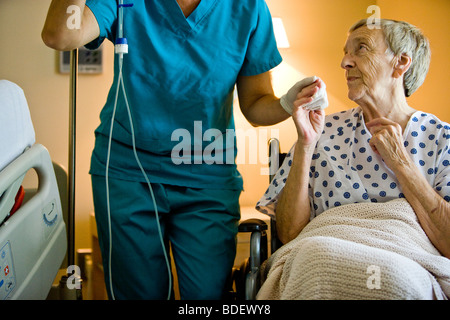 Senior Frau im Rollstuhl weiter, um im Krankenzimmer Krankenschwester Stockfoto