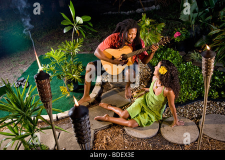 Jamaikanische junge Mann serenading schöne Frau im tropischen Garten Stockfoto