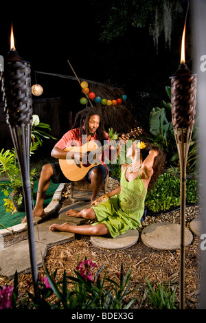 Jamaikanische junge Mann serenading schöne Frau im tropischen Garten Stockfoto