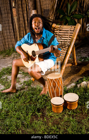 Jamaikanische Jüngling mit Dreadlocks spielen Gitarre und Bongos auf tropischen Insel Stockfoto