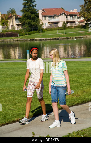 Tween-Tweens Hispanic und kaukasische Mädchen im Teenageralter gehen und sprechen im Park abhängen. Herr © Myrleen Pearson Stockfoto