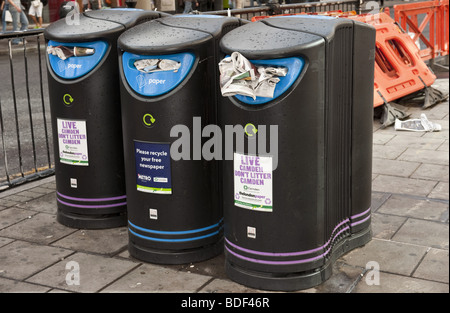 Drei große Kunststoff Straße Abfallbehälter für freie Hand, Zeitungen randvoll auf London Straße Asphalt recycling verwendet Stockfoto