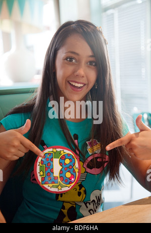 Ein Mädchen, die ihren 18. Geburtstag auf ihrem Geburtstag Abzeichen und lächelnd genießen Stockfoto