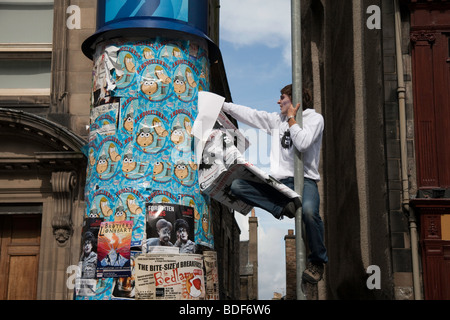 Ein Mann versucht, in Aufmachungen einige Plakate seiner Show im Rahmen des Edinburgh Fringe Festival 2009 Stockfoto