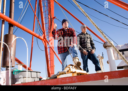 Junge Fischer in karierten Hemden, stehend auf Fischerboot Stockfoto