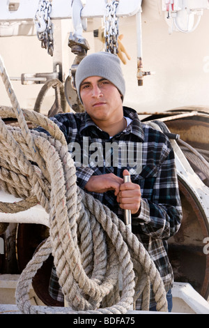 Junge Fischer im karierten Hemd stehen auf Fischerboot mit Seilen Stockfoto