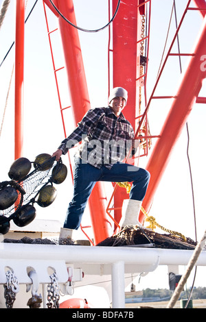 Junge Fischer im karierten Hemd ziehen Netze am Fischerboot Stockfoto