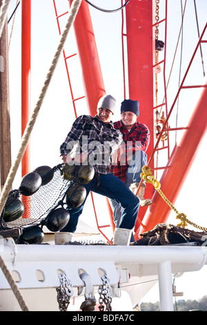 Junge Fischer in karierten Hemden ziehen Netze am Fischerboot Stockfoto