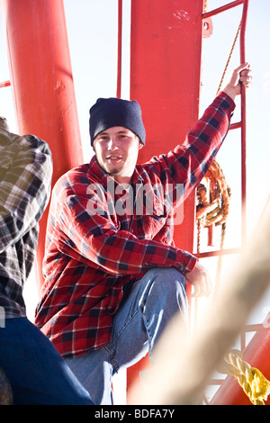 Junge Fischer im karierten Hemd mit Fischerboot Stockfoto