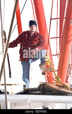 Junge Fischer im karierten Hemd mit Fischerboot Stockfoto