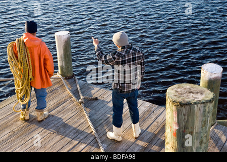 Rückansicht der junge Fischer stehen am Pier mit Seilen, ein Mann zeigte Stockfoto