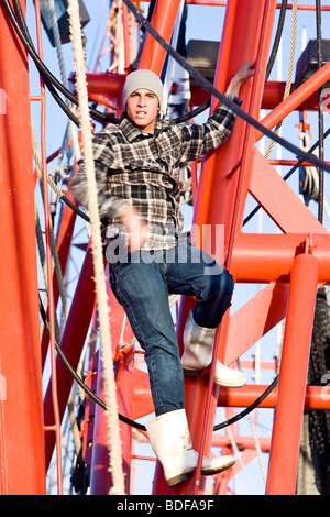 Junge Fischer im karierten Hemd Klettern auf Fischerboot Stockfoto