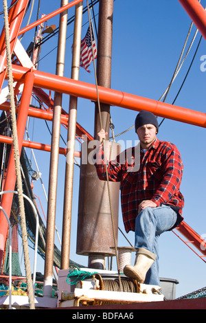 Junge Fischer im karierten Hemd mit Fischerboot Stockfoto