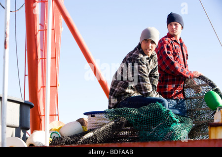Junge Fischer in karierten Hemden mit Netzen auf Fischerboot Stockfoto