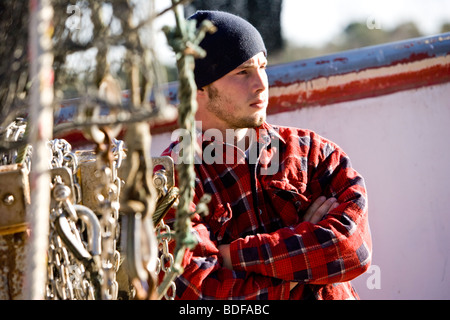 Junge Fischer im karierten Hemd stehen in der Nähe von Fischerboot Stockfoto