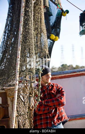 Junge Fischer im karierten Hemd stehen in der Nähe von Fischerboot Stockfoto