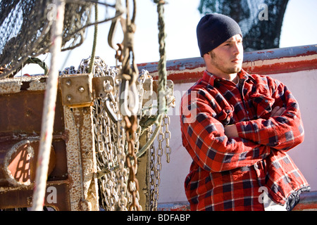 Junge Fischer im karierten Hemd stehen in der Nähe von Fischerboot Stockfoto