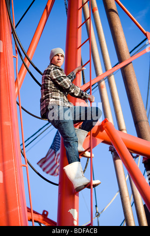 Junge Fischer im karierten Hemd Aufstieg auf Fischerboot Stockfoto