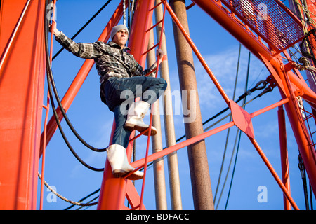 Junge Fischer im karierten Hemd Aufstieg auf Fischerboot Stockfoto