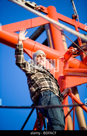 Junge Fischer im karierten Hemd winken von Leiter mit Fischerboot Stockfoto