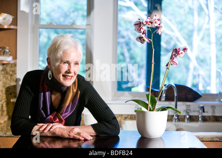 Ältere Frau sitzt in Küche Stockfoto