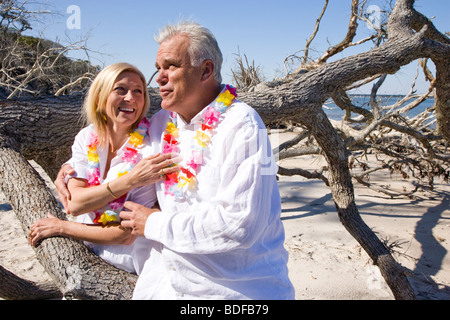 Paar mittleren Alters in Leis am Strand Stockfoto