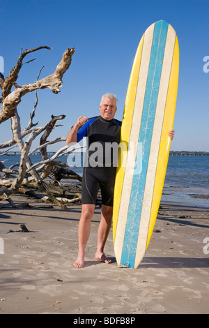 Mann mittleren Alters im Neoprenanzug mit Surfbrett am Strand Stockfoto