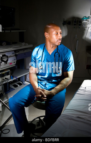 Afrikanisch-amerikanischer Arzt in Scrubs sitzen im Krankenzimmer Stockfoto