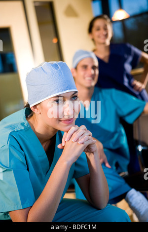Junger Arzt in Scrubs mit Kollegen im Hintergrund Stockfoto