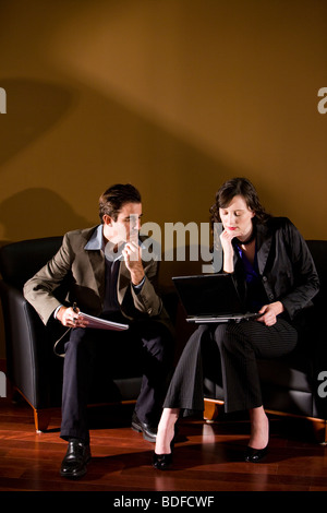 Geschäftsleute im Lounge-Bereich mit Laptop sitzen Stockfoto