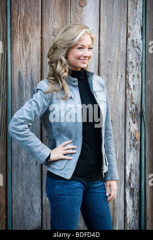 Junge Frau, die außen Holzgebäude Stockfoto