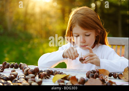 Mädchen spielt im Garten mit Kastanien, Kastanien Igel, Kastanien Figuren Stockfoto