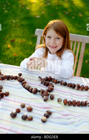 Mädchen spielt im Garten mit Kastanien, Kastanien-Figuren Stockfoto