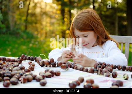 Mädchen spielt im Garten mit Kastanien, Kastanien-Figuren Stockfoto