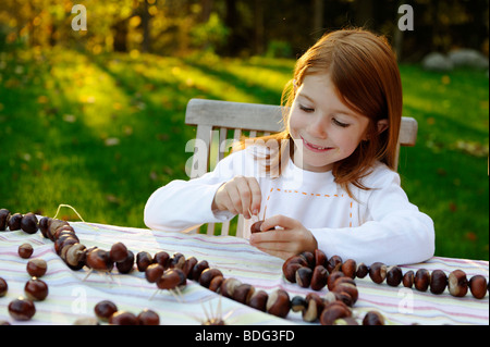 Mädchen spielt im Garten mit Kastanien, Kastanien Igel, Kastanien Figuren Stockfoto