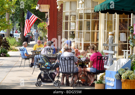 Straßenszene in Falmouth, Cape Cod mit Menschen, die Essen an Tischen im Freien in einem Café und Schaufenster im Sommer. USA Stockfoto