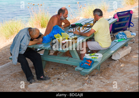 Männer saßen auf einer Bank im Schatten spielt Schach mit alten Honig Verkäufer in Assos schlafend auf der griechischen Insel Kefalonia Griechenland GR Stockfoto