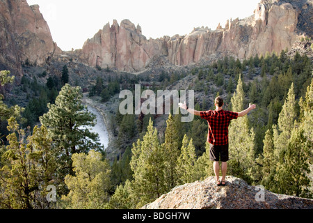 Ein Mann in einem karierten Hemd zeichnet sich durch seine Arme weit offen mit Blick auf das Crooked River Tal. Stockfoto