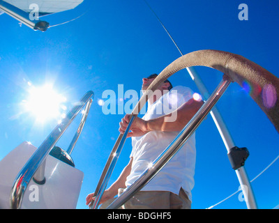 Ein Skipper Lenkung an Bord einer Yacht unter blauem Himmel während der Fahrt in Pittwater am Nordufer von Sydney, Australien. Stockfoto